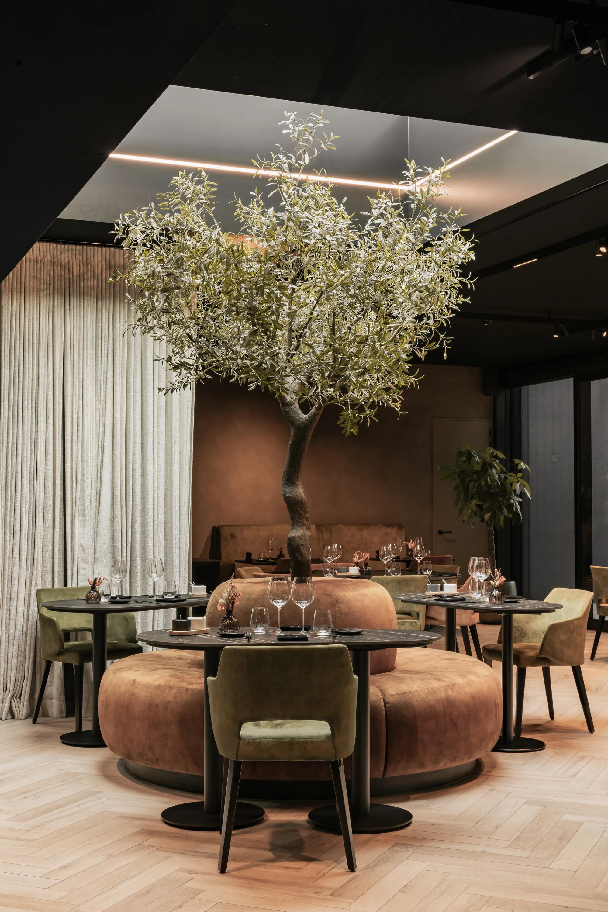 Tafel aan ronde zetel en boom in Restaurant Herenhuis Izegem