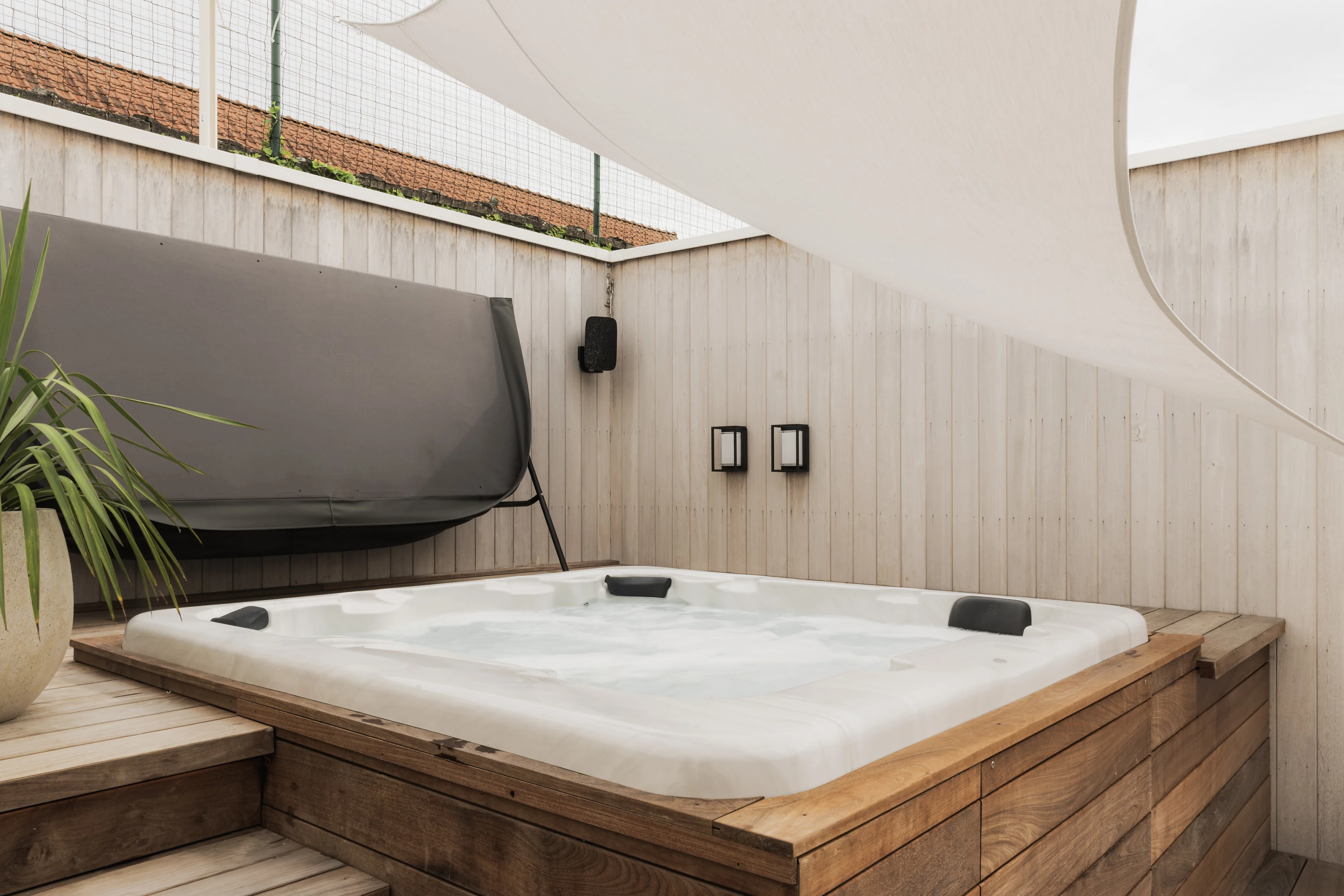 Jacuzzi met zeildoek en zicht op houten muur.